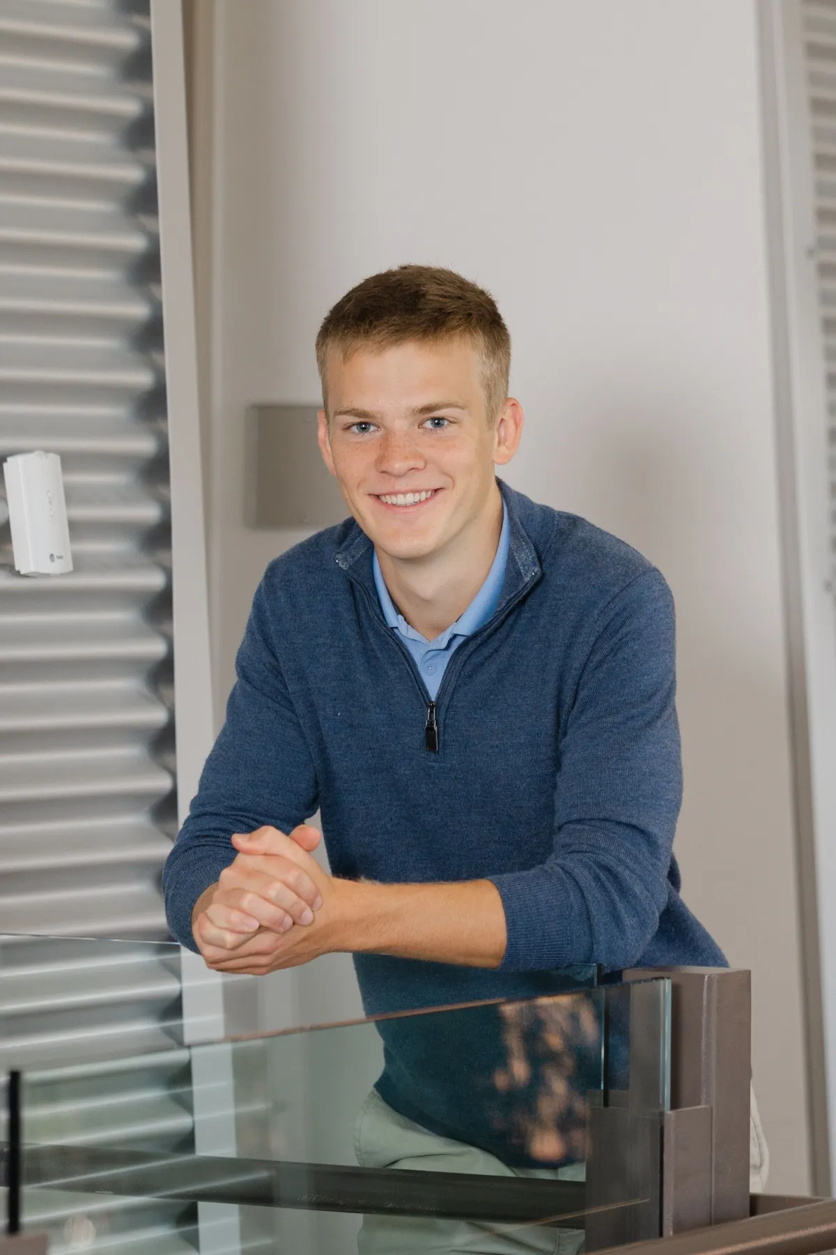 Jared Swift, founder of Swift Sites, in a blue quarter-zip, leaning on a glass railing and smiling